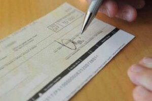 Immagine di un assegno bancario mentre viene firamto